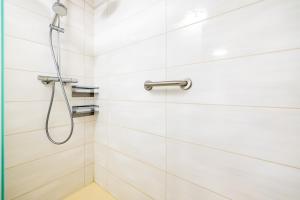 a shower in a bathroom with white tiles at Exklusive Ferienwohnung am Südstrand mit Meerblick & Balkon Wohnung 10 in Wilhelmshaven