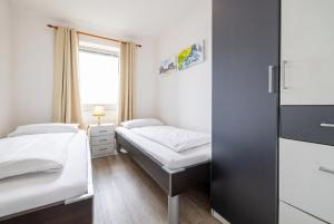 a small room with two beds and a window at Exklusive Ferienwohnung am Südstrand mit Meerblick & Balkon Wohnung 10 in Wilhelmshaven