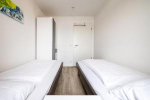 two beds in a room with white walls at Exklusive Ferienwohnung am Südstrand mit Meerblick & Balkon Wohnung 10 in Wilhelmshaven