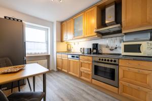 a kitchen with wooden cabinets and a table and a microwave at Exklusive Ferienwohnung am Südstrand mit Meerblick & Balkon Wohnung 10 in Wilhelmshaven +10 photos