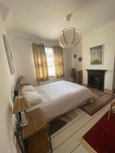 a bedroom with a large white bed and a fireplace at Glen Villa - 3 bedroom house - Stroud town centre in Stroud