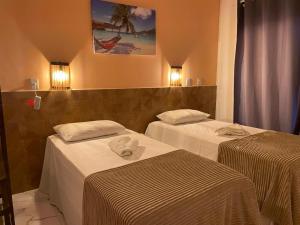 two beds in a hotel room with white sheets at Recanto das Oliveiras in Corumbau