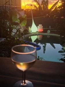 a glass of wine sitting next to a swimming pool at Chalet en bois accés piscine in La Possession +14 photos