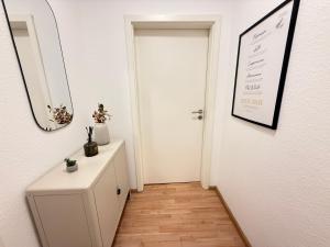 a hallway with a white door and a table and a mirror at Stage One City in Andernach