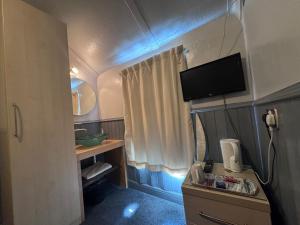 a small bathroom with a tv on the wall at Mallow View Hotel in Cleethorpes