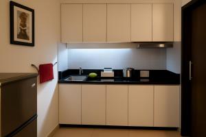 a kitchen with white cabinets and a sink at Riviera Hermitage in Arpora