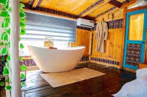 a bathroom with a tub in a room with wooden walls at Santorini by Busybee Lake Cabins in Mwanza