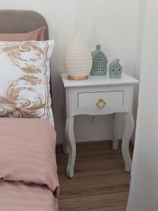 a white nightstand with a vase on it next to a bed at Secret Garden House in Surduk +5 photos