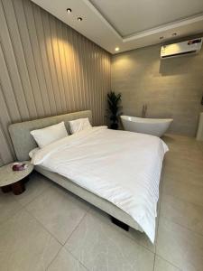 a bedroom with a large white bed and a bath tub at شاليهات دبليو العمارية W Chalet in Al ‘Ammārīyah +15 photos
