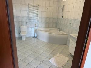 a bathroom with a tub and a toilet and a sink at Pensjonat Trzy Stawy in Jelcz +16 photos