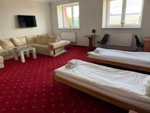 a hotel room with two beds and a couch at Pensjonat Trzy Stawy in Jelcz