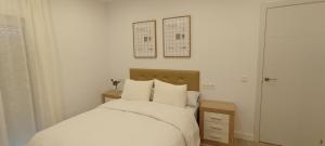 a bedroom with a bed with white sheets and pillows at Casa Conde in Alfarnate