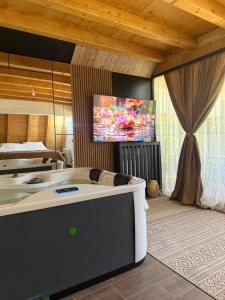 a room with a bath tub with a tv on the wall at Etno selo Vukovic Bijelo Polje in Bijelo Polje