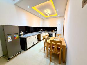 a kitchen with a table and a refrigerator at Palm & Tide Kenitra Residence in Kenitra