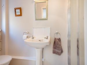 a white bathroom with a sink and a shower at Beacons Cottage-Uk36406 in Bronllys