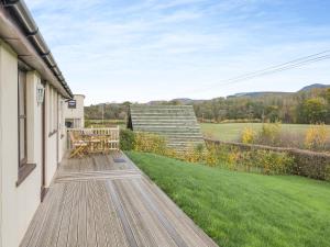 a deck with a table and chairs on the side of a house at Beacons Cottage-Uk36406 in Bronllys