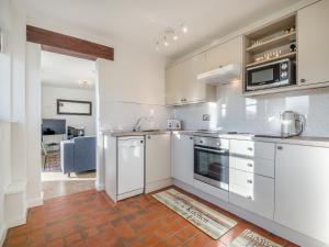 a kitchen with white cabinets and stainless steel appliances at Beacons Cottage-Uk36406 in Bronllys
