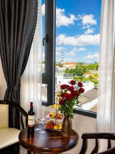 a table with a vase of flowers and a window at Laimeront Dalat Hotel & Apartment in Da Lat