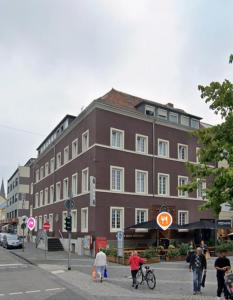 a large brown building on a city street with people at Drei Schweizer Hotel in Neuwied