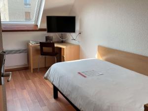 a hotel room with a bed and a desk with a television at ibis Alençon in Alençon