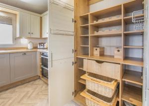 a kitchen with white cabinets and wooden shelves at Lower Hyde in Shanklin