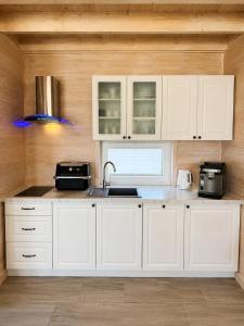 a kitchen with white cabinets and a sink at Silver Park Resort 10m do plaży in Gąski +19 photos