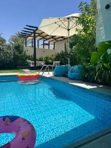 a swimming pool with an umbrella and an inflatable at شاليهات دبليو العمارية W Chalet in Al ‘Ammārīyah
