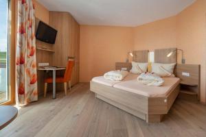 a bedroom with a bed and a desk and a television at Hotel Mohren in Hagnau