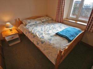 a bedroom with a bed with a blue comforter and a window at St Abbs Cottage in Belford
