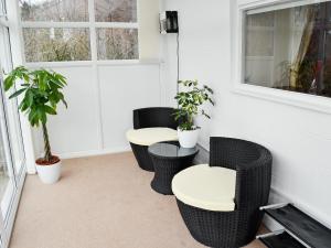 a porch with three chairs and two tables and a window at Cheviot Cottage in Belford