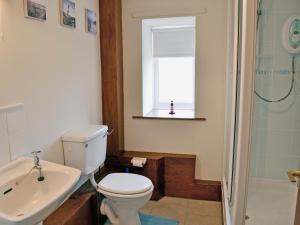 a bathroom with a toilet and a sink and a window at Cheviot Cottage in Belford