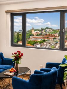 a living room with blue chairs and a large window at Laimeront Dalat Hotel & Apartment in Da Lat