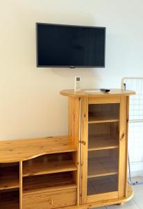 a tv on a wall with a wooden entertainment center at Ilona Apartmanházak in Gyenesdiás