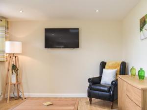 a living room with a chair and a television on the wall at Sherwood Forest Lodge 2 in Clipstone