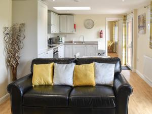 a black leather couch with yellow pillows in a living room at Sherwood Forest Lodge 2 in Clipstone