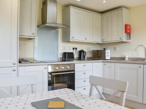 a kitchen with white cabinets and a table and chairs at Sherwood Forest Lodge 2 in Clipstone +12 photos