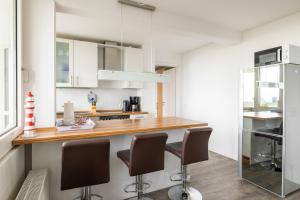 a kitchen with white cabinets and a counter with bar stools at Komfortable Ferienwohnung für 2 am Südstrand mit Wintergarten & Meerblick Wohnung 12 in Wilhelmshaven