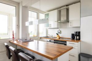 a kitchen with white cabinets and a wooden counter top at Komfortable Ferienwohnung für 2 am Südstrand mit Wintergarten & Meerblick Wohnung 12 in Wilhelmshaven