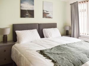 a bedroom with a bed with white sheets and pillows at Gwynfa in Rhyl +6 photos