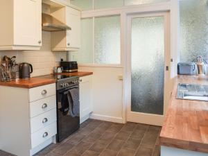 a kitchen with white cabinets and a stove top oven at Gwynfa in Rhyl