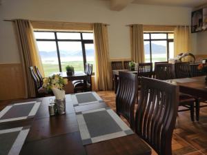 a dining room with a table and chairs and windows at Zim Retreat Tsokar in Pongunagu