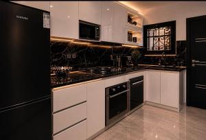 a kitchen with white cabinets and black appliances at Massa Residence Meublé Yaounde in Yaoundé