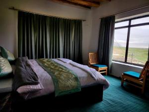 a bedroom with a bed and a large window at Zim Retreat Tsokar in Pongunagu
