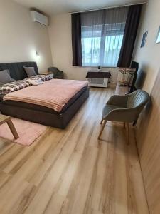 a bedroom with a bed and a chair at Móra Corner Apartman Mezőkövesd in Mezőkövesd +24 photos