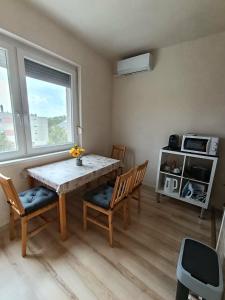 a dining room with a table and chairs and a window at Móra Corner Apartman Mezőkövesd in Mezőkövesd