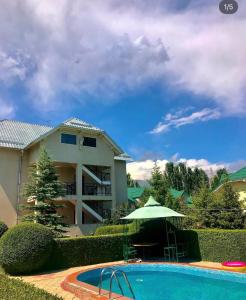 a house and a swimming pool with an umbrella at Алтын Мезгил in Korumdy +8 photos