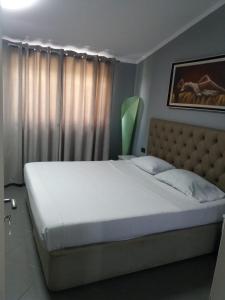 a bedroom with a large white bed with a large window at Vila Ali Demi in Tirana