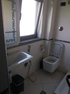 a bathroom with a toilet and a sink and a window at Vila Ali Demi in Tirana