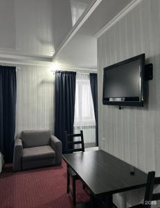 a room with a table and a chair and a television at Oral City Hotel in Oral
