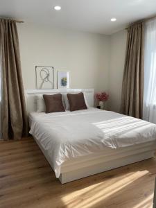 ein weißes Schlafzimmer mit einem großen weißen Bett und braunen Kissen in der Unterkunft ZimApartment in Jõhvi